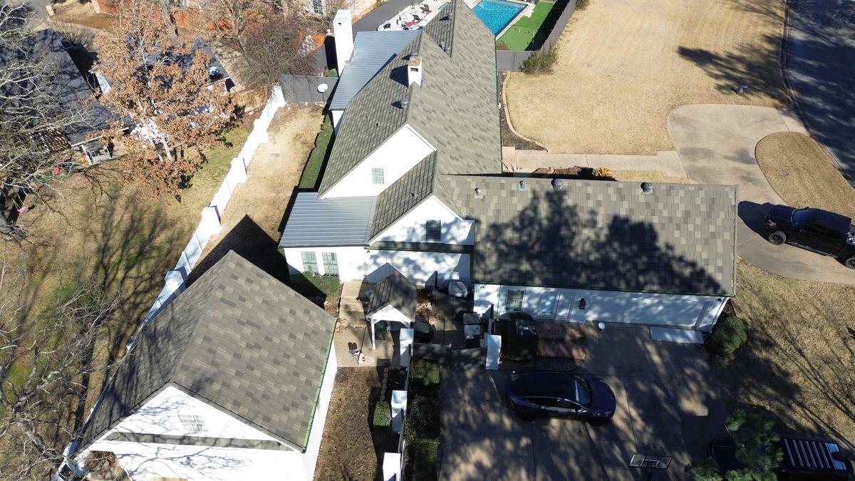 High drone view along a white house and a detached building, both with dark roofs