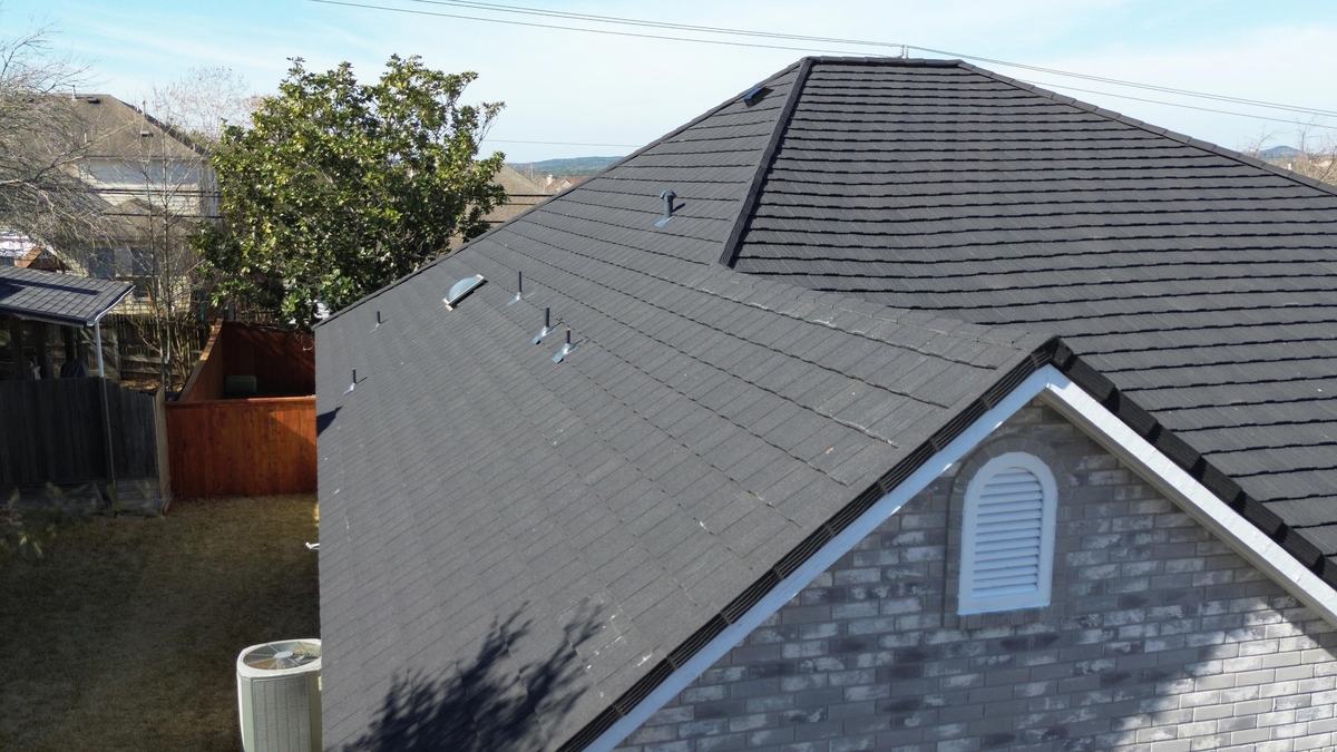 Close drone view of a charcoal roof slope and gable vent on a brick home