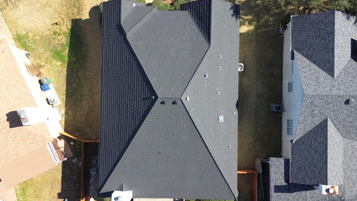 Straight-down drone view of a charcoal hip roof between two neighboring homes
