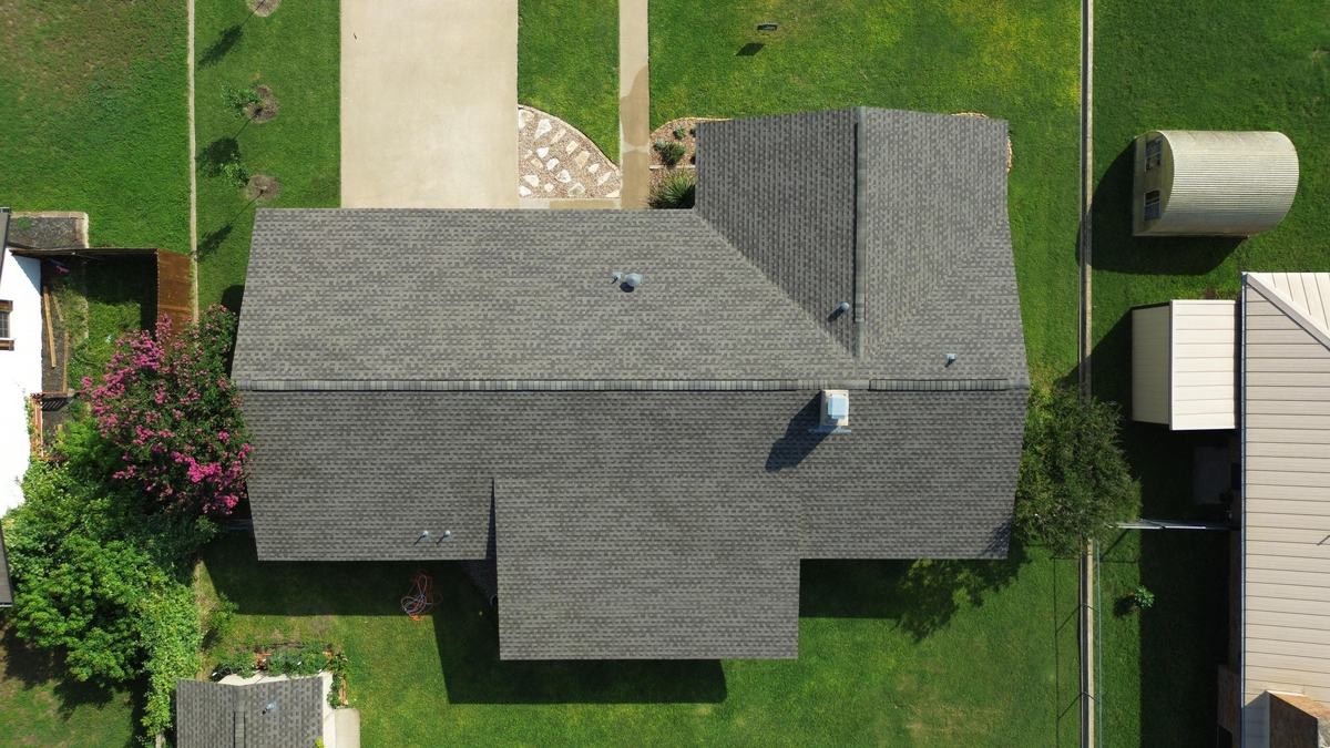 Straight-down drone view of a gray roof on a ranch home with a green yard